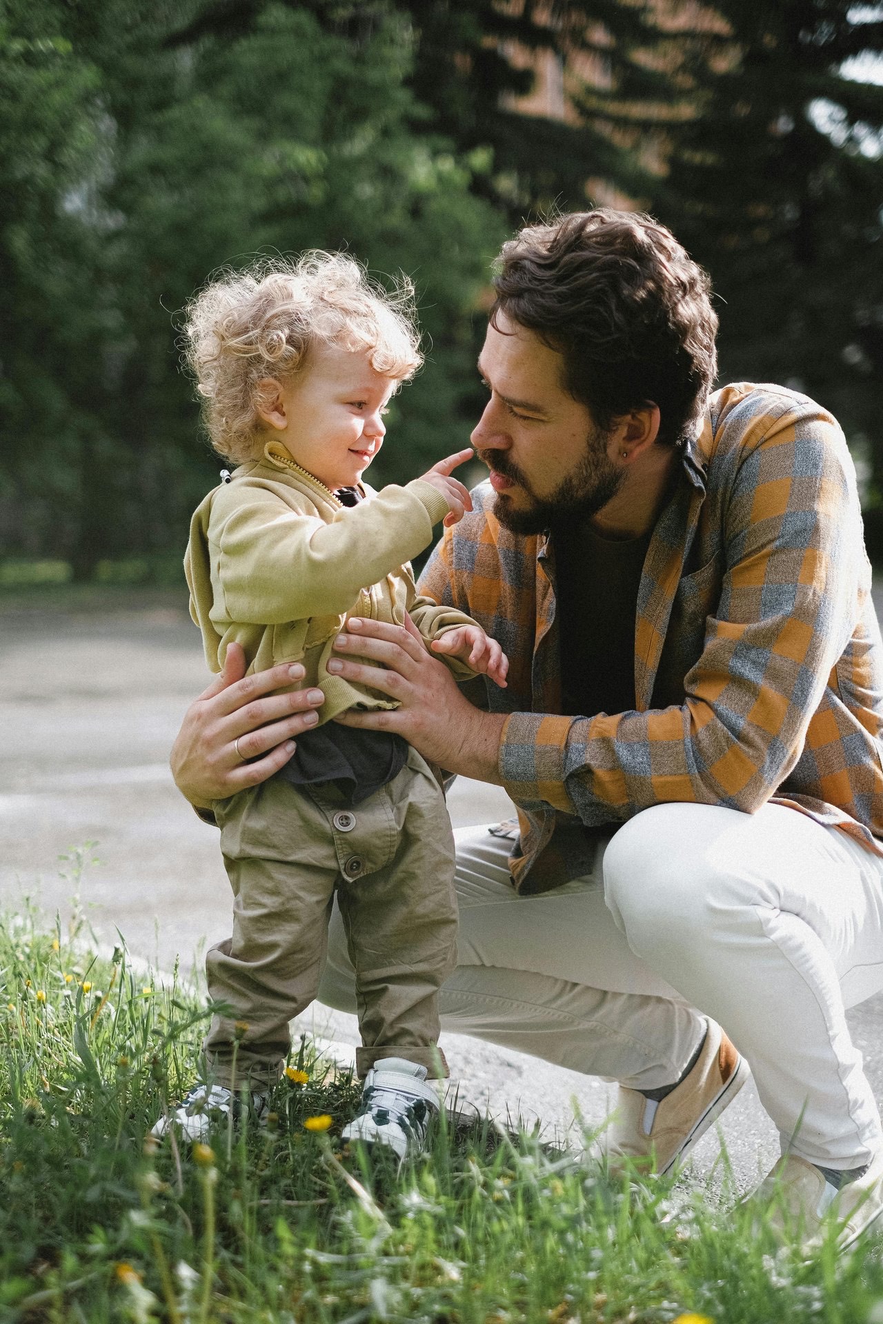 A father crouching down to hold his young son outdoors