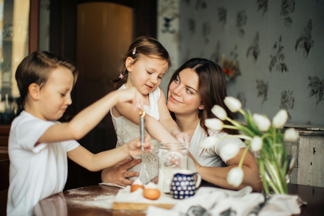 A mother baking with her two young children