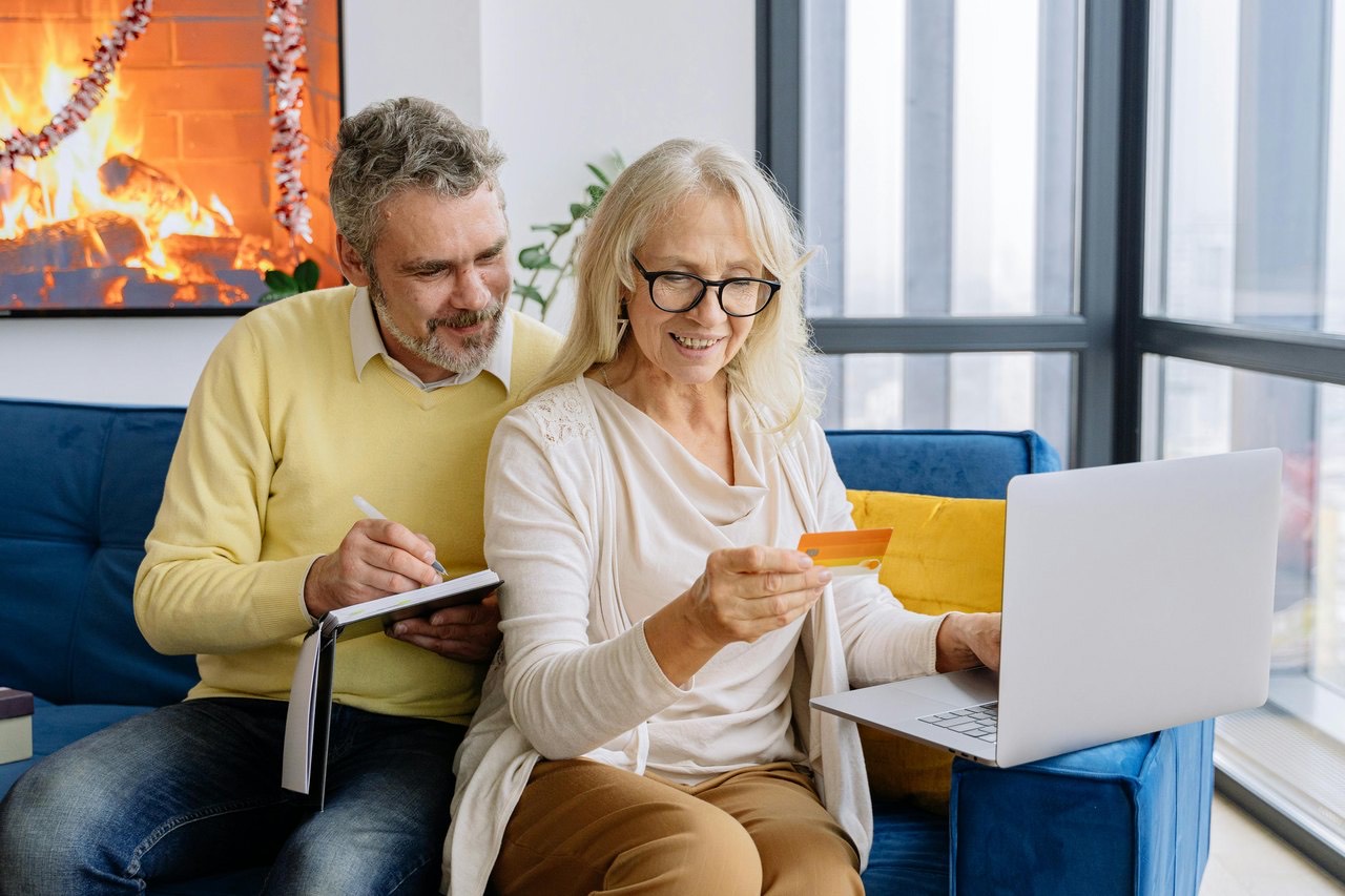An older couple reviewing paperwork together with a laptop