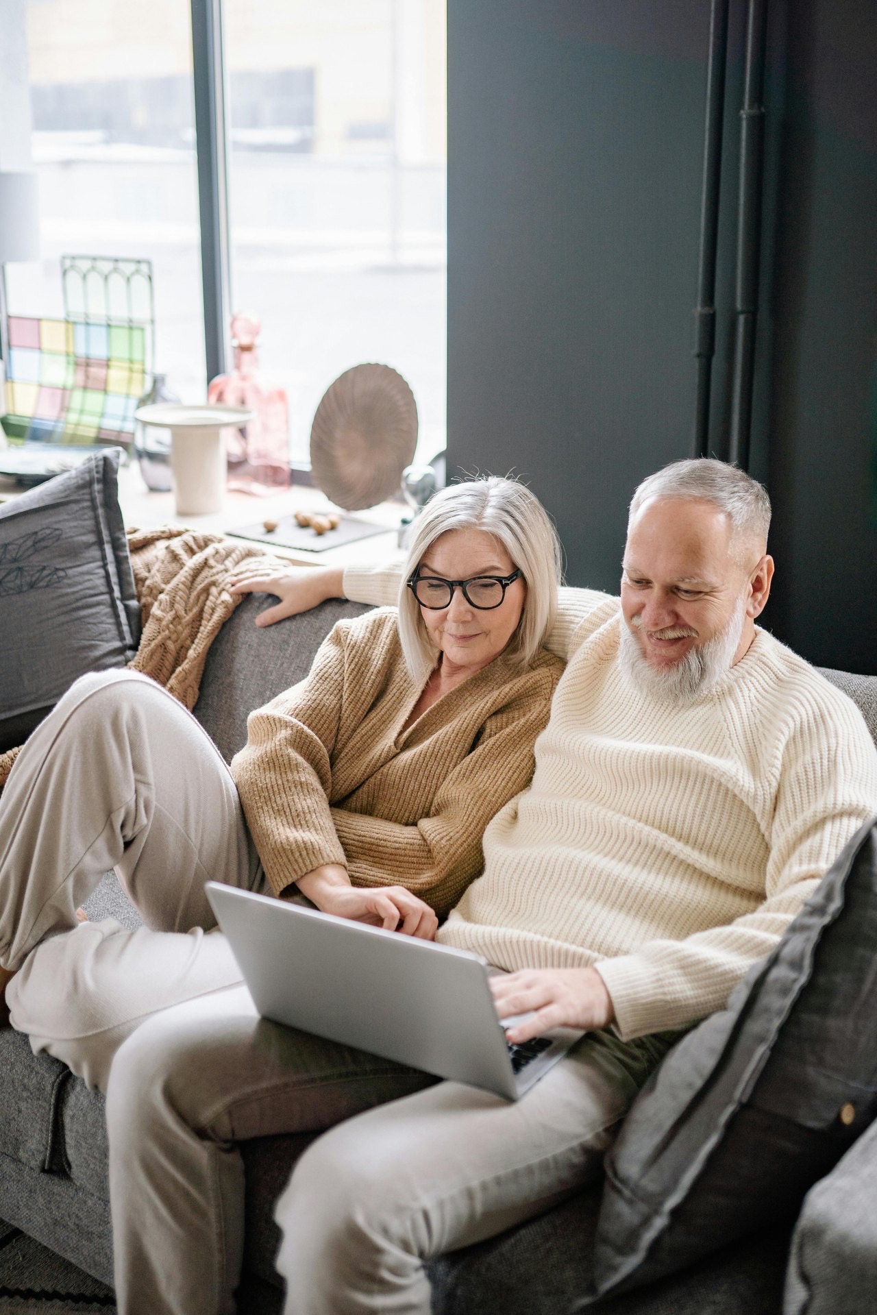 An older couple relaxing together on a sofa with a laptop