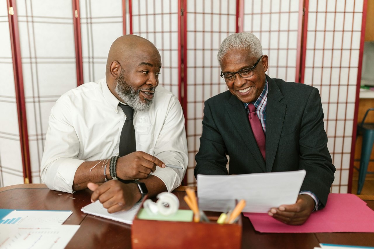Two men discussing paperwork across a desk